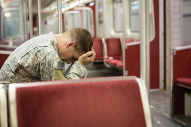 Soldier with head in hands on subway