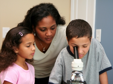 teacher and students at microscope
