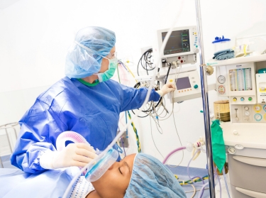 Anesthesiologist checking monitors while sedating patient 