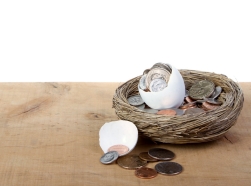 A cracked open egg with coins spilling out