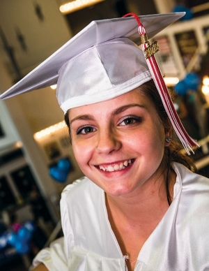 A smiling graduate in a white cap and gown