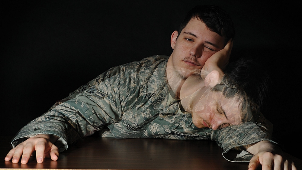 A soldier sitting at a table falls asleep.