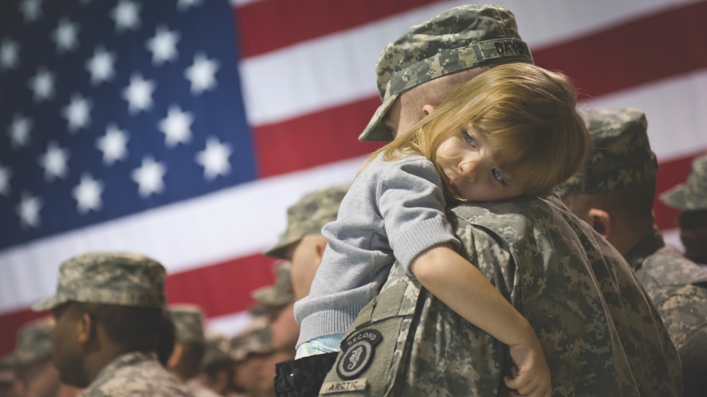 U.S. Army soldier holds his daughter after a deployment ceremony at the Alaska National Guard Armory