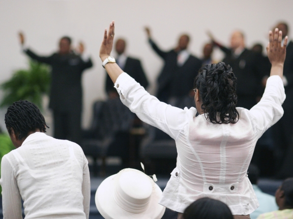 African American woman with hands raised in worship at a church service