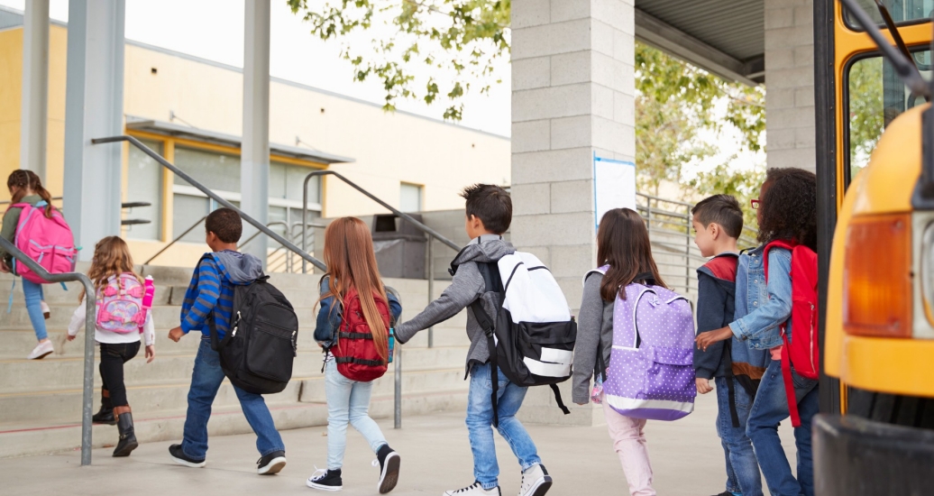 Elementary school children arrive at school by bus