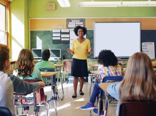 A teacher speaks at the front of the class