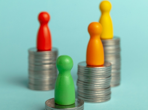 Game pieces atop stacks of coins of various heights, depicting income inequity