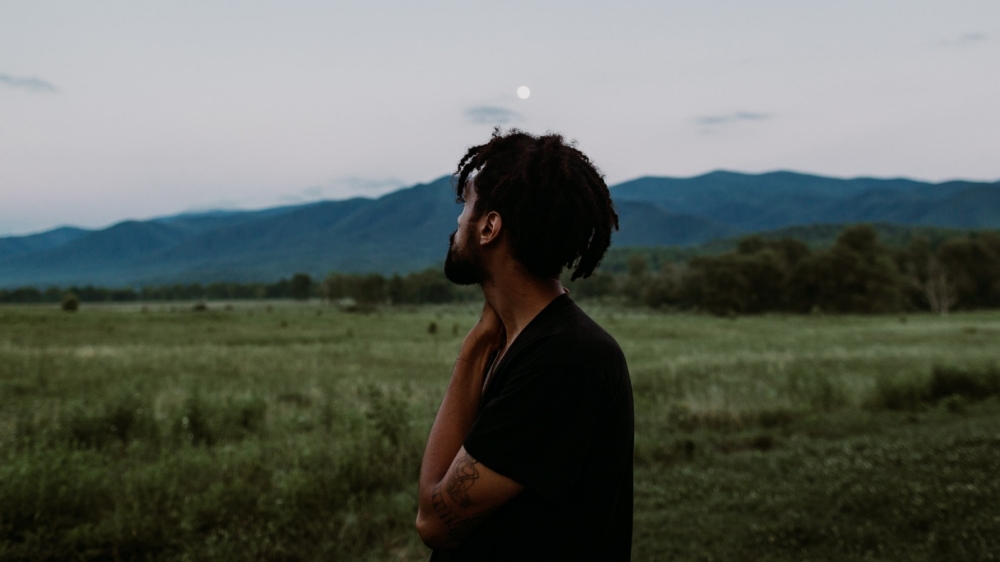 Person standing in a field looking toward mountains in the distance. Photo by Ivana Cajina/Unsplash