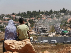 Palestinians watch Israeli heavy machinery demolishing vacant apartment blocs by order of Israel's high court, in the West Bank Jewish settlement of Beit El near Ramallah July 29, 2015