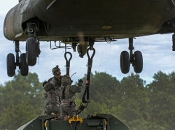Army reservists hook a bay bridge to a CH-47 Chinook helicopter using a sling harness during a slingload training operation at Fort Chaffee, Arkansas