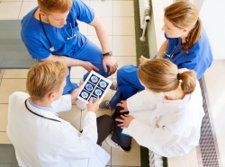 Doctor using a digital tablet to show results to a team of medical staff