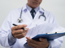A doctor wearing a white coat holding a clipboard