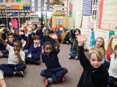 Young students raising their hands in a classroom