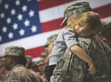 U.S. Army soldier holds his daughter after a deployment ceremony at the Alaska National Guard Armory