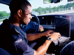 A police officer working on a computer in a patrol car