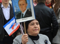 A woman holds a placard with a portrait of Russian President Vladimir Putin during a celebration of the third anniversary of Russia's annexation of Crimea in Simferopol, March 16, 2017