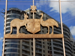 The Australian Coat of Arms in metal hangs on the glass wall of a building