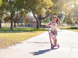 Little girl riding a scooter in a park