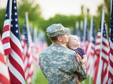 American soldier with daughter, surrounded by American flags