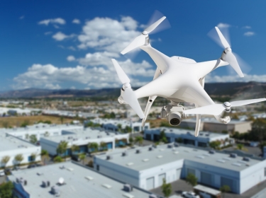 Unmanned aircraft system (uav) quadcopter drone in the air over commercial buildings