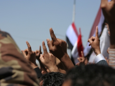 Anti-government protesters outside Sana'a University raise their fingers and fists in the air while chanting for a new Yemen, February 25, 2011