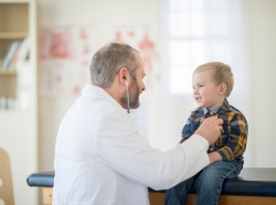 Male doctor listening to a young boy's heartbeat