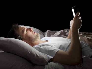 Man in bed looking at a tablet