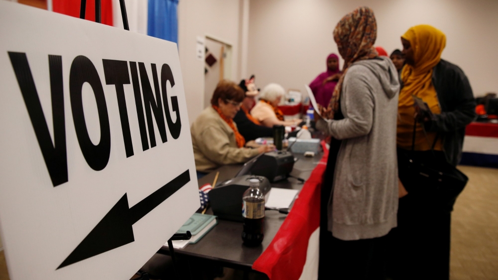 Voters stand near a voting sign before casting ballots during early voting