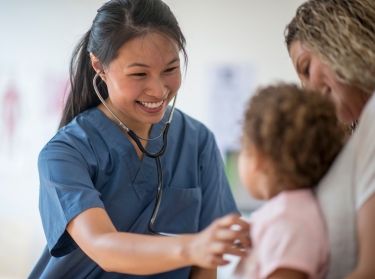 Female nurse using a stethoscope to listen to a little girl's heartbeat