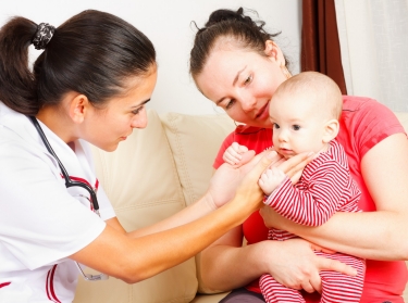 A medical professional visiting an infant and her mother at home