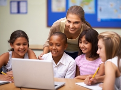 A teacher and four students looking at a laptop