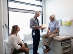 Doctor consulting with an elderly patient while a female family member looks on