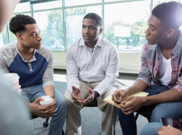 African American men seated in a circle having a discussion