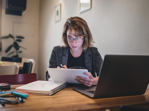 A teacher at a desk with a tablet and a laptop