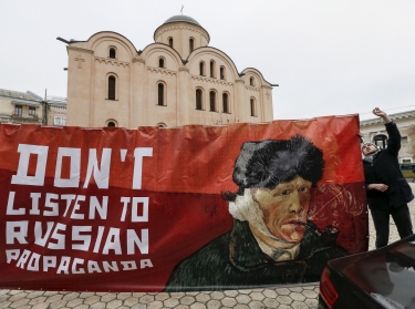 An activist outside the Dutch embassy in Kiev, Ukraine, holds a banner that says not to listen to Russian propaganda, February 5, 2016, photo by Gleb Garanich/Reuters