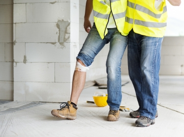 Construction worker helping an injured worker walk
