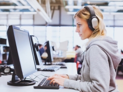 Student in headphones working on computer in the library or classroom of university, photo by anyaberkut/Adobe Stock