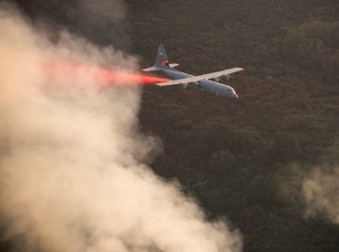 A C-130J Hercules from the 146th Airlift Wing, California Air National Guard, sprays fire retardant ahead of the leading edge of the Thomas Fire, Dec. 13, 2017, photo by Master Sgt. Brian Ferguson/U.S. Air Force