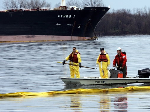 Emergency workers float along an oil collection boom in front of Athos I after it spilled 30,00 gallons of crude oil into the Delaware River in Philadelphia, November 28, 2004