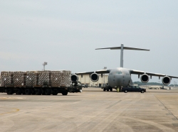 A C-17 from Elmendorf Air Force Base, Alaska, sits on the ramp here while food and cold weather supplies prepare to be loaded onto another C-17 (not pictured) from Hickam Air Force Base, Hawaii, Feb. 8., photo by Senior Airman Jeremy McGuffin/U.S. Air Force