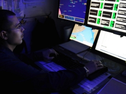 intelligence specialist monitors automatic identification systems aboard the aircraft carrier USS George H.W. Bush