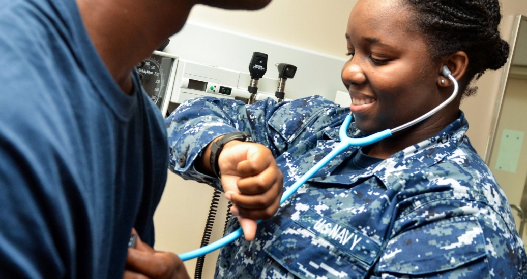 A member of the U.S. Navy takes a patient's blood pressure