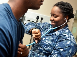 A member of the U.S. Navy takes a patient's blood pressure