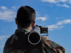 A soldier aims a portable anti-aircraft weapon at a target