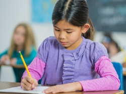 A girl is concentrating hard on a test. She is using a pencil to write, photo by FatCamera/Getty Images