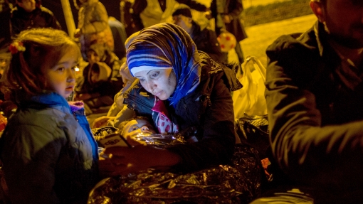 A refugee mother looks at her smartphone after arriving by rubber raft from Turkey to the Greek island of Lesbos near the port city of Mytilene, Greece, March 9, 2016