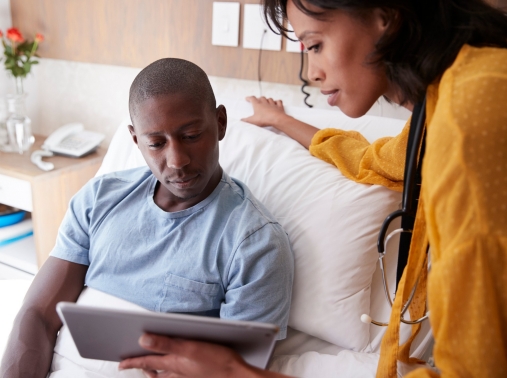 Doctor with digital tablet talking with a patient in a hospital bed