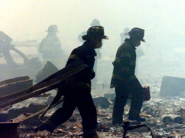 A group of firefighters walk amid rubble near the base of the destroyed World Trade Center in New York on September 11, 2001