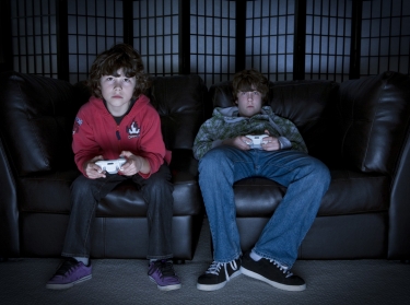 Two boys sitting on a couch playing video games, photo by Sean Davis/Fotolia