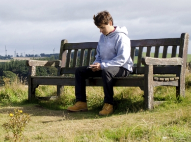 Man on a bench in countryside using mobile